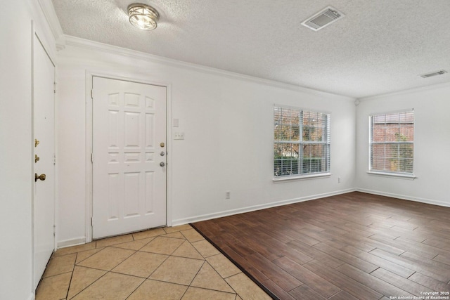 entryway featuring ornamental molding, a textured ceiling, and light hardwood / wood-style floors