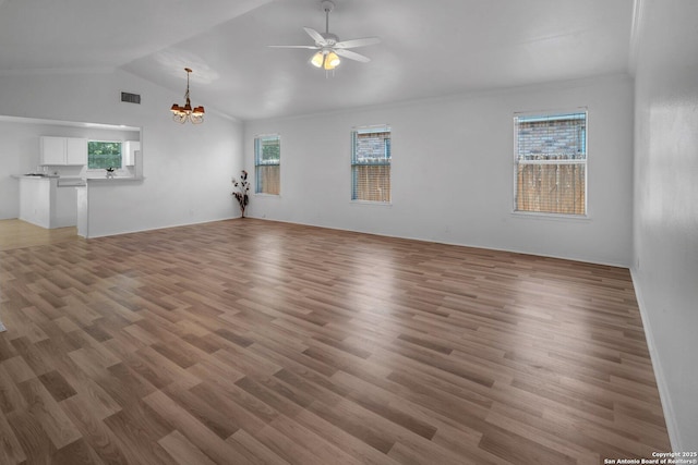 unfurnished living room with hardwood / wood-style flooring, ceiling fan with notable chandelier, and vaulted ceiling