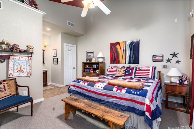 carpeted bedroom with a towering ceiling, connected bathroom, and ceiling fan