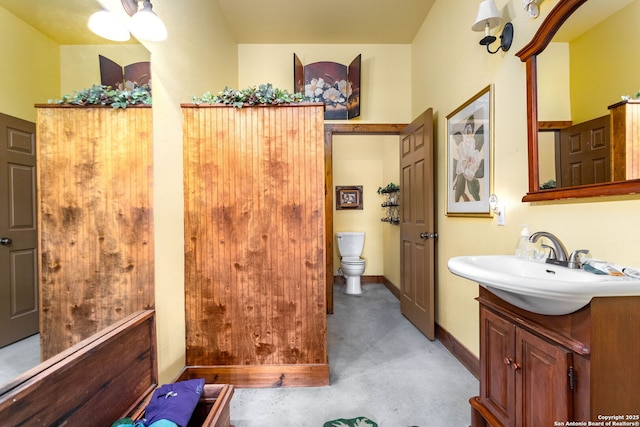 bathroom with concrete flooring, vanity, and toilet