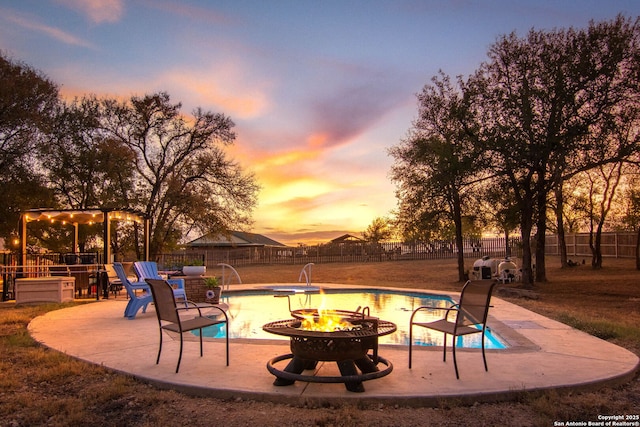 pool at dusk featuring pool water feature and a fire pit