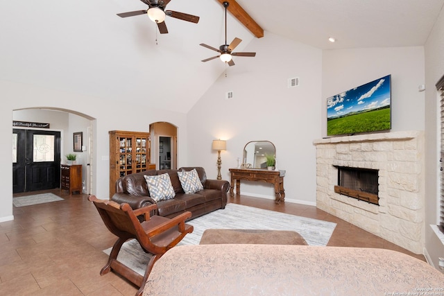 living room featuring high vaulted ceiling, a fireplace, beamed ceiling, tile patterned flooring, and ceiling fan