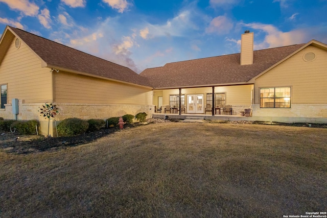 back house at dusk featuring a yard, a patio area, and french doors