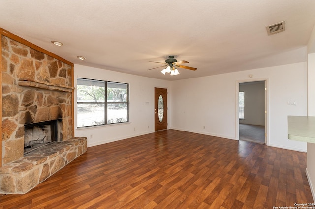 unfurnished living room with ceiling fan, a fireplace, dark hardwood / wood-style flooring, and a textured ceiling