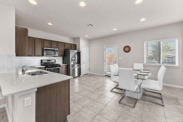 kitchen with sink, a breakfast bar area, backsplash, light stone counters, and stainless steel appliances