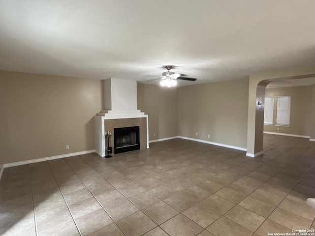 unfurnished living room with a tiled fireplace, tile patterned floors, and ceiling fan