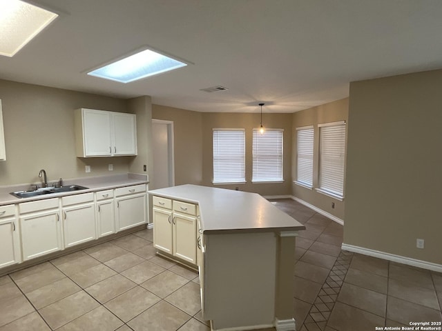 kitchen featuring sink, hanging light fixtures, white cabinets, and a kitchen island