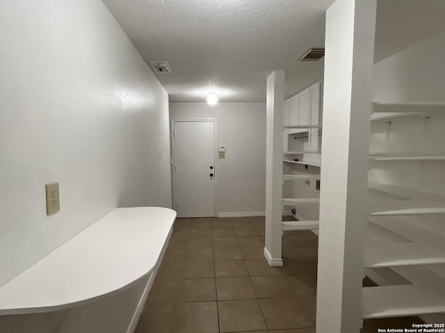 hall featuring dark tile patterned floors and a textured ceiling