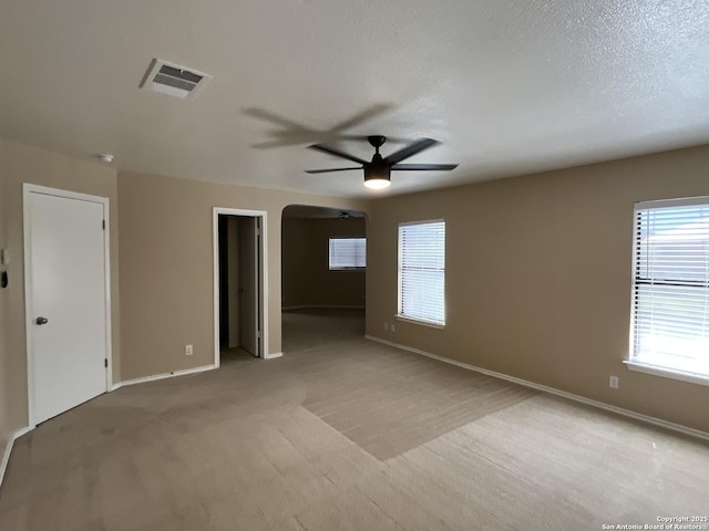 unfurnished room featuring ceiling fan, light colored carpet, and a textured ceiling