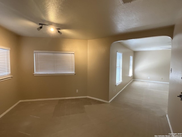 unfurnished room with carpet floors, a textured ceiling, and plenty of natural light