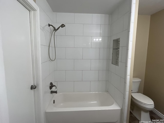 bathroom with toilet and tiled shower / bath combo