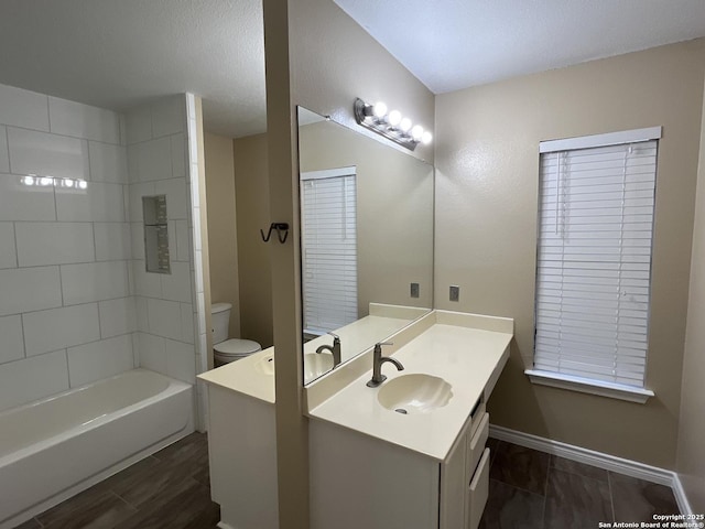 full bathroom with vanity, tiled shower / bath, and toilet