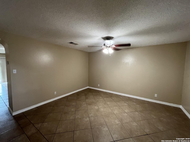 empty room featuring dark tile patterned floors, a textured ceiling, and ceiling fan