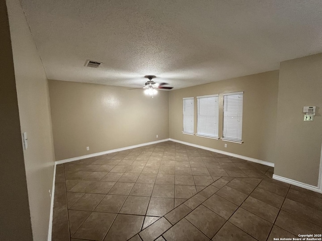 spare room featuring dark tile patterned floors, a textured ceiling, and ceiling fan