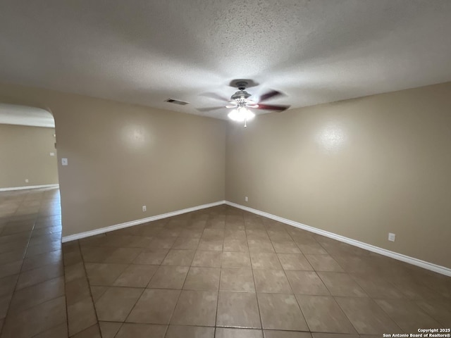 tiled spare room featuring a textured ceiling and ceiling fan