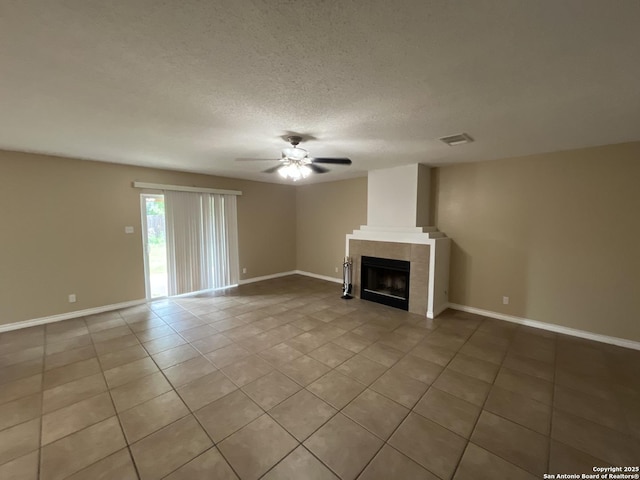 unfurnished living room featuring light tile patterned flooring, ceiling fan, a tile fireplace, and a textured ceiling