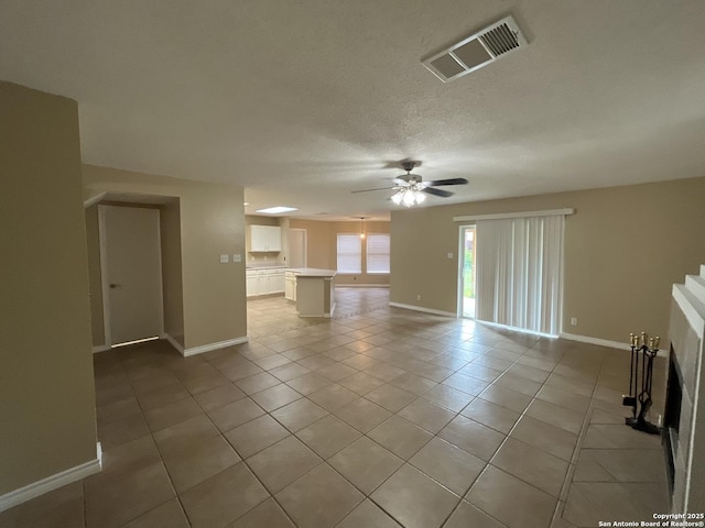 unfurnished living room featuring ceiling fan, a textured ceiling, and light tile patterned floors