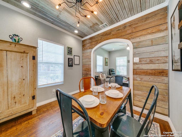 dining area featuring ornamental molding, dark wood-type flooring, wooden ceiling, and wood walls