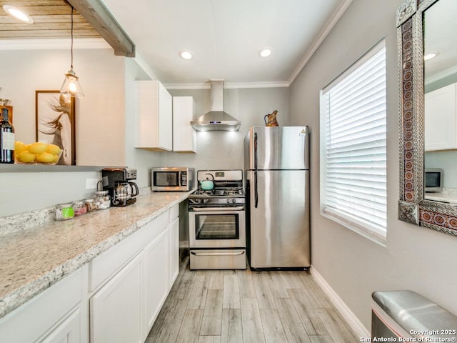 kitchen with decorative light fixtures, white cabinets, ornamental molding, stainless steel appliances, and wall chimney exhaust hood