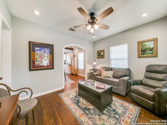 living room featuring dark wood-type flooring and ceiling fan