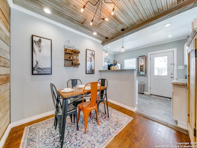 dining area featuring beam ceiling, wood-type flooring, wooden ceiling, and crown molding