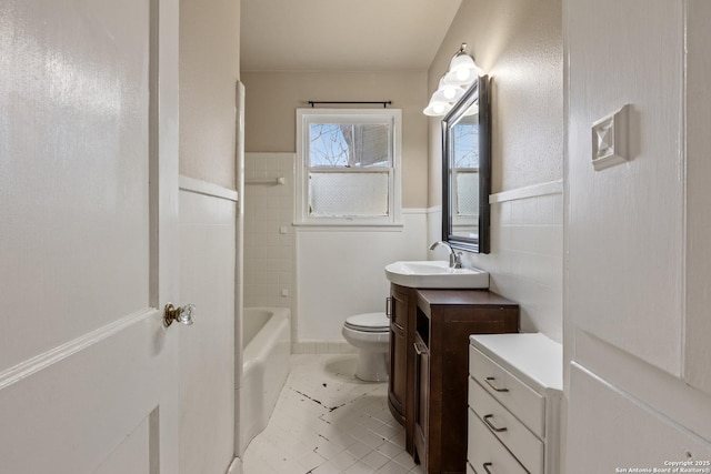 full bathroom with vanity, tiled shower / bath, tile walls, and toilet