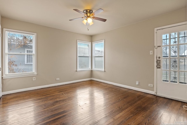 empty room with dark wood-type flooring, ceiling fan, and a wealth of natural light