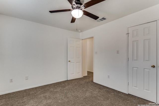 unfurnished bedroom with ceiling fan and dark colored carpet