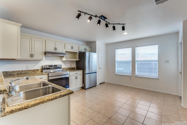 kitchen featuring appliances with stainless steel finishes, sink, light tile patterned floors, and a textured ceiling