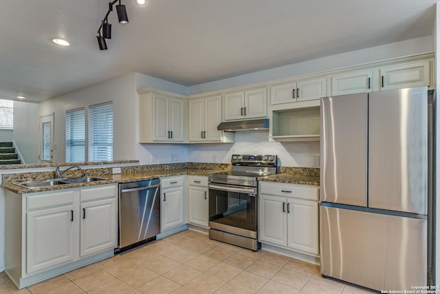 kitchen featuring appliances with stainless steel finishes, sink, white cabinets, dark stone counters, and light tile patterned floors