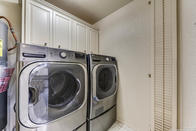 washroom with cabinets, light tile patterned flooring, washer and dryer, and a textured ceiling