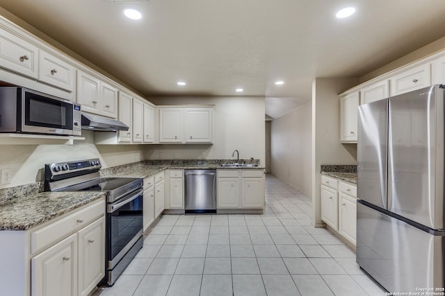 kitchen featuring sink, light tile patterned floors, dark stone countertops, stainless steel appliances, and white cabinets