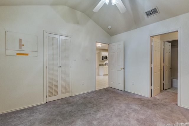 unfurnished bedroom featuring lofted ceiling, light colored carpet, a closet, and ceiling fan