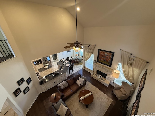 living room featuring dark hardwood / wood-style flooring, ceiling fan, and high vaulted ceiling