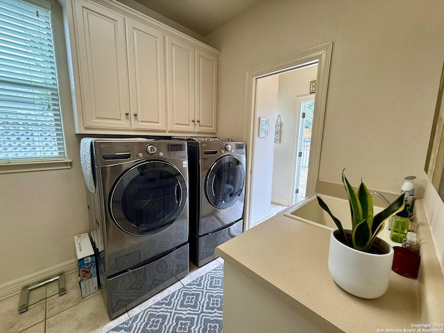 laundry room featuring cabinets, washing machine and dryer, a wealth of natural light, and light tile patterned floors