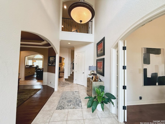 entrance foyer with a high ceiling, crown molding, and light hardwood / wood-style floors