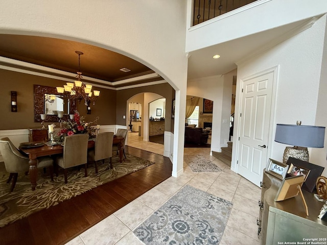 tiled dining area featuring a towering ceiling, ornamental molding, a raised ceiling, and a chandelier