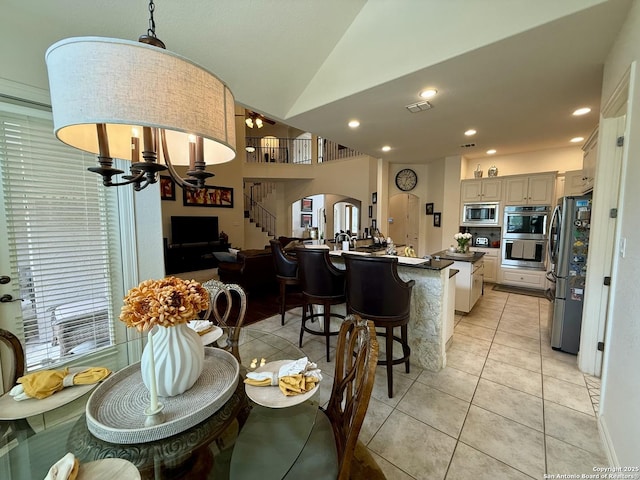 tiled dining space featuring lofted ceiling and a notable chandelier