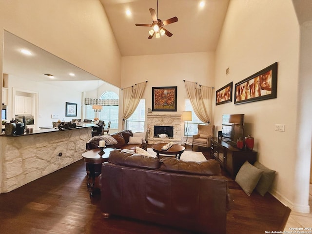 living room with dark hardwood / wood-style floors, ceiling fan, a fireplace, and high vaulted ceiling