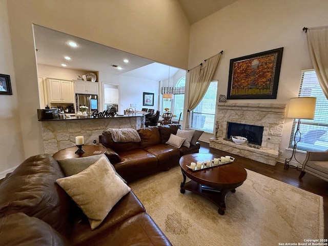 living room featuring a towering ceiling, a fireplace, and wood-type flooring