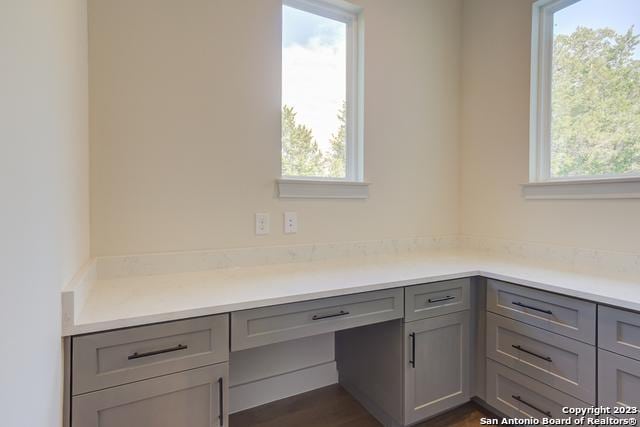 unfurnished office with dark wood-type flooring and built in desk