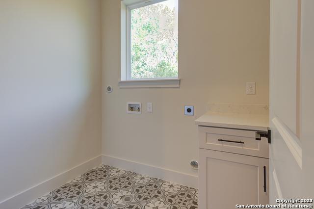 laundry area with cabinets, electric dryer hookup, washer hookup, and light tile patterned floors