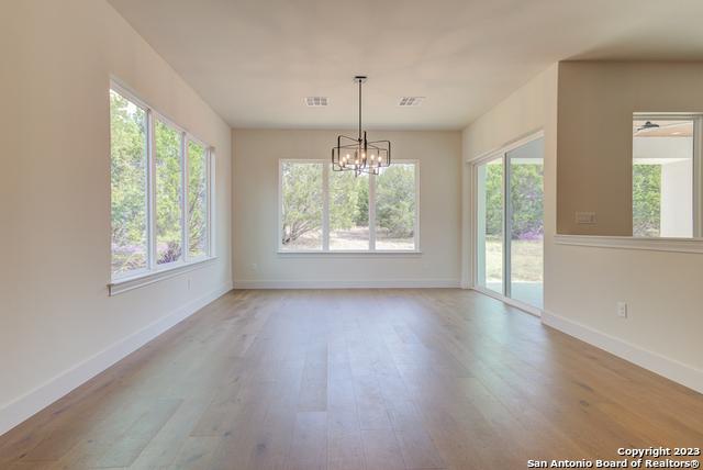 unfurnished dining area featuring a chandelier and light hardwood / wood-style flooring