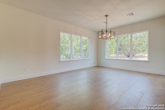 spare room with a chandelier and light hardwood / wood-style floors