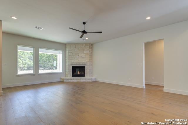 unfurnished living room with a fireplace, ceiling fan, and light wood-type flooring