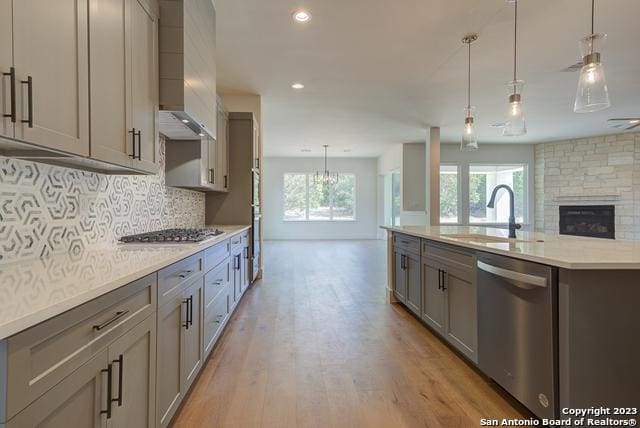 kitchen featuring an island with sink, appliances with stainless steel finishes, sink, and decorative light fixtures