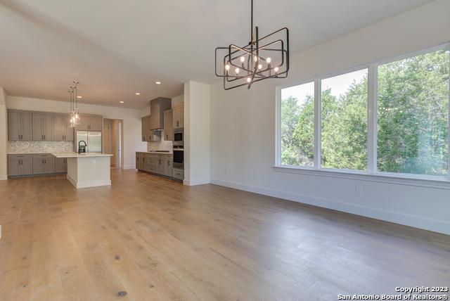 unfurnished living room featuring a notable chandelier, a healthy amount of sunlight, and light wood-type flooring