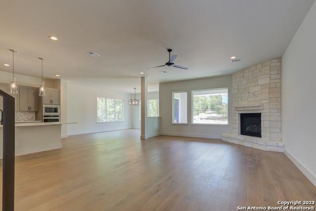 unfurnished living room with a fireplace, a healthy amount of sunlight, and light wood-type flooring