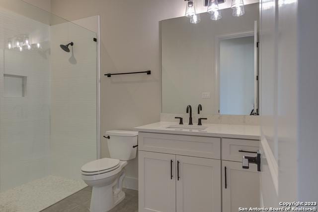 bathroom with tile patterned floors, vanity, toilet, and a tile shower