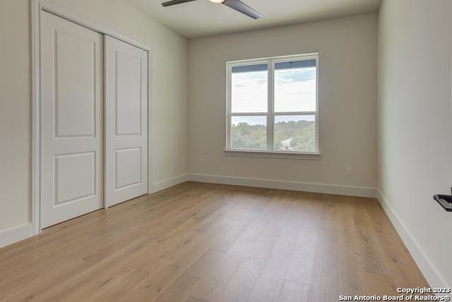 unfurnished bedroom with ceiling fan, a closet, and light wood-type flooring